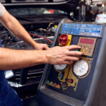 Mechanic checks air conditioning system in car auto service
