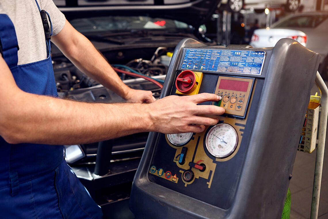 Mechanic checks air conditioning system in car auto service